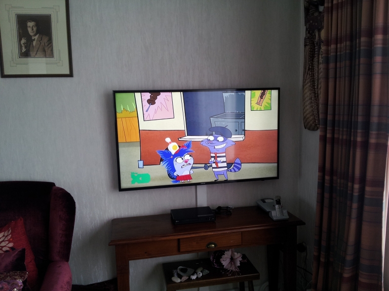 Ook bij u thuis leveren wij een nette installatie op, zoals hier bij het ophangen van een UHD TV.
